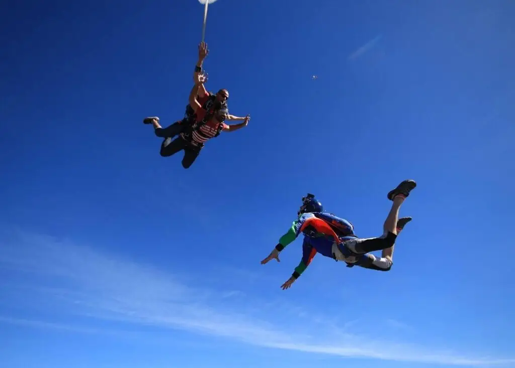 A tandem skydive pair free falling with a videographer filming