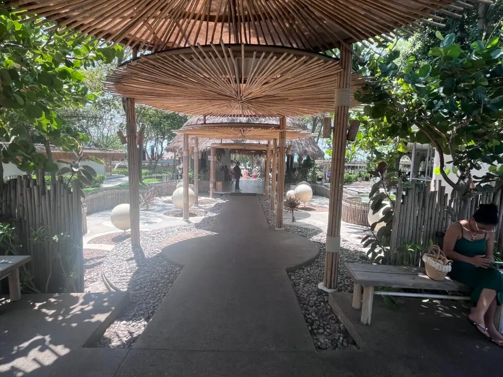 Spacious seating under straw-roofed canopies at The Oxygen Beachside Oasis, perfect for relaxing by the sea.